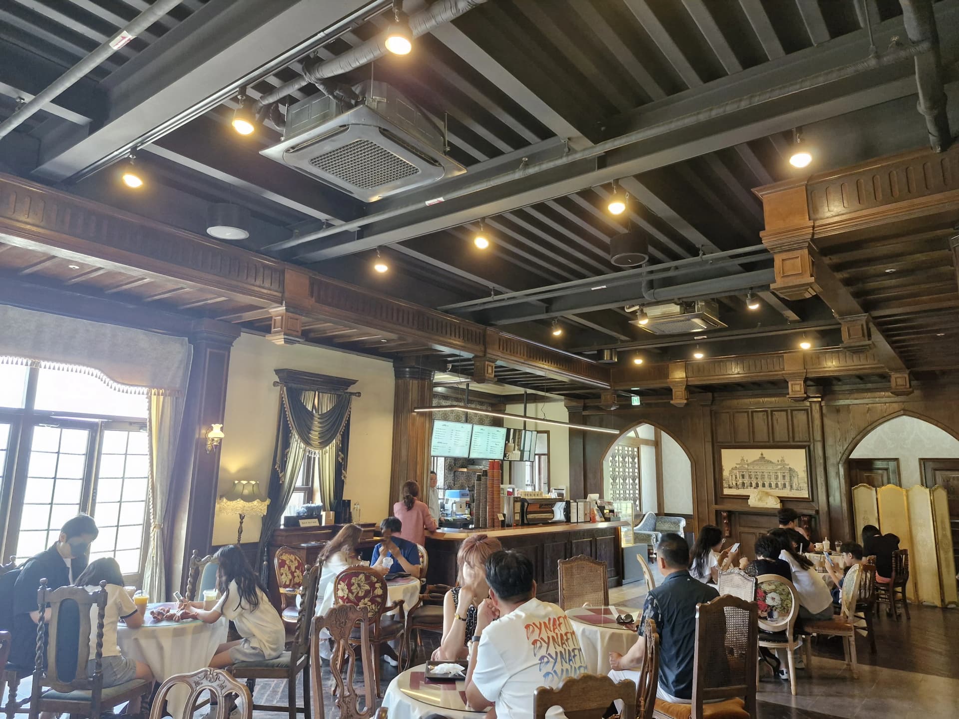 Interior kafe lantai 2 Glory Hotel dengan furnitur antik dan kayu gelap | 하이제이에스비