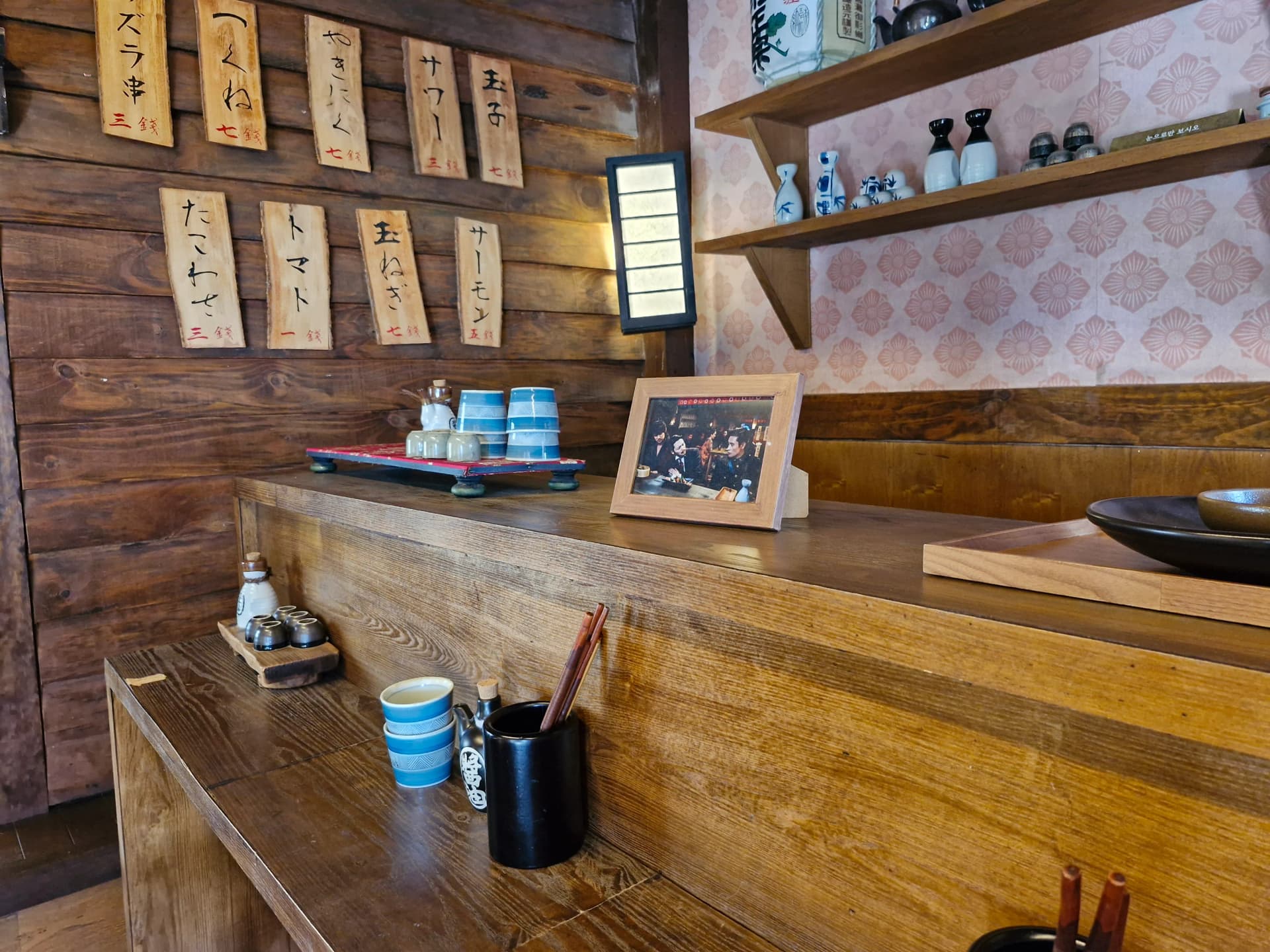 Papan menu kayu dengan tulisan Jepang dan satuan mata uang kuno di dinding | 하이제이에스비