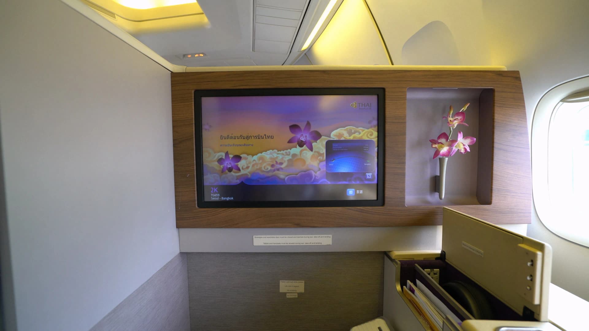 타이항공 퍼스트클래스 23인치 IFE 모니터에 태국어 환영 문구와 난초 모티브 인터페이스