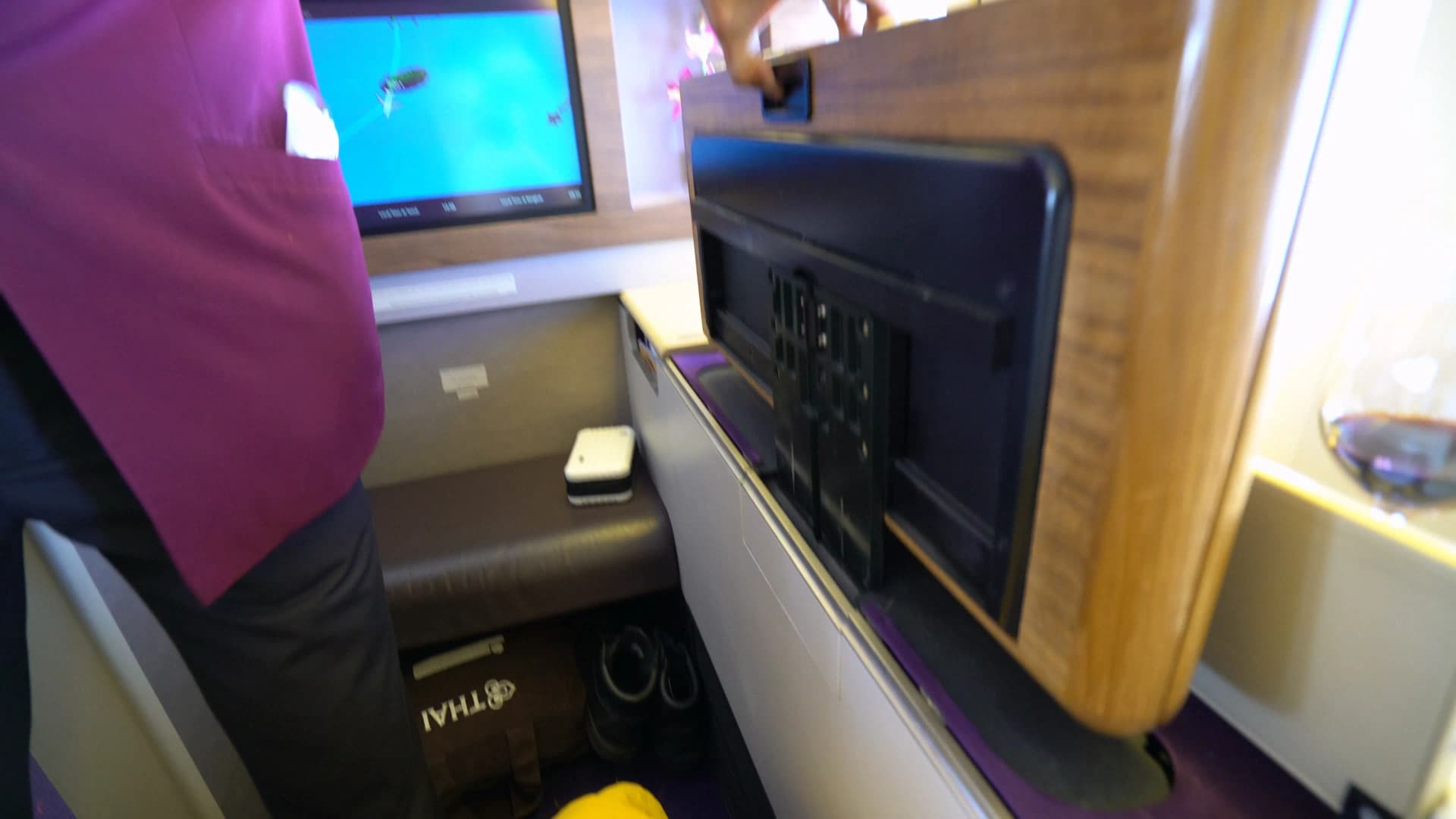 타이항공 퍼스트클래스 남자 승무원이 벽면에서 우드 접이식 테이블을 꺼내 펼치는 모습