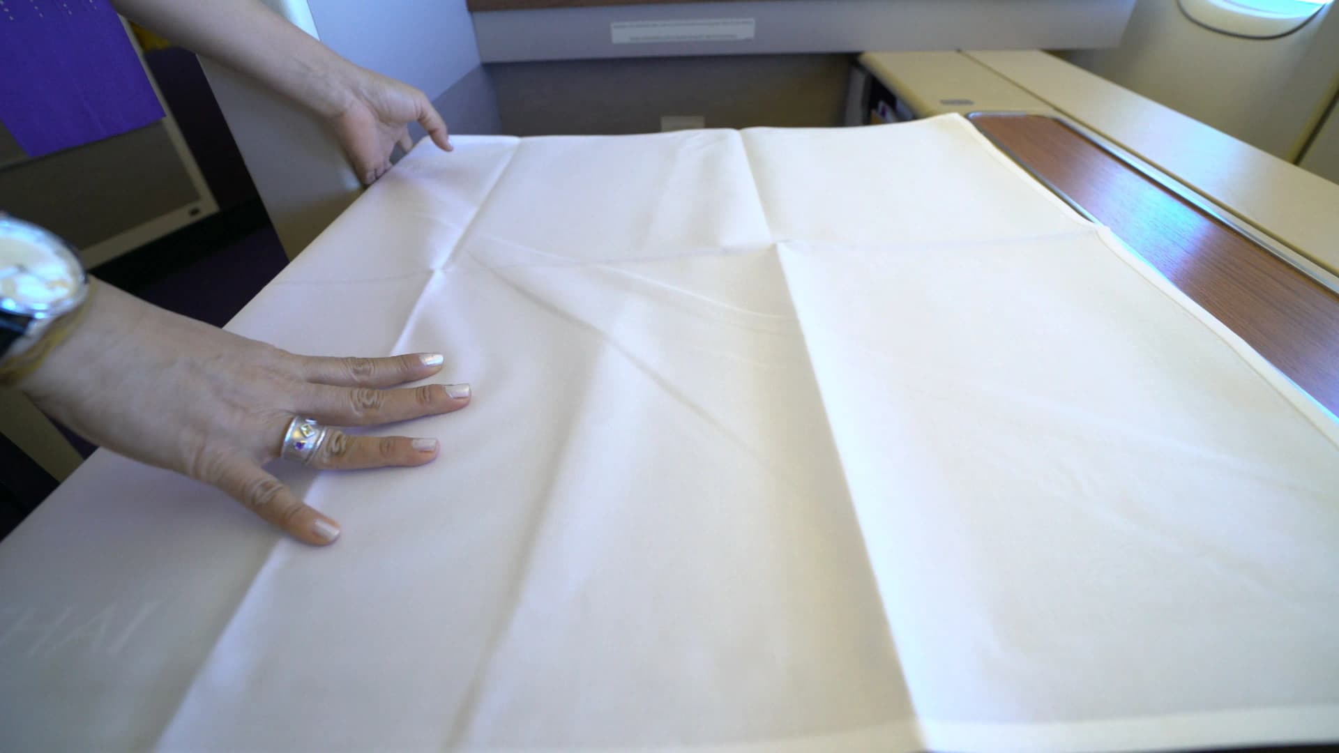 타이항공 퍼스트클래스 여자 승무원이 테이블 위에 흰색 식탁보를 깔아주는 장면