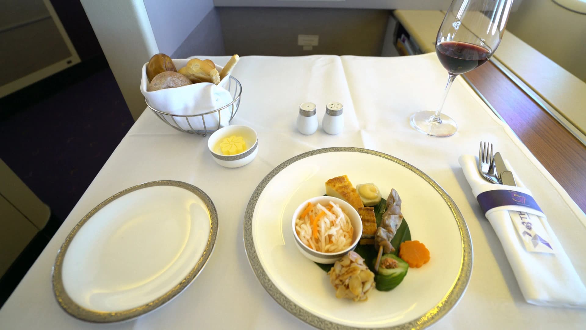 타이항공 퍼스트클래스 퍼스트 코스 전체 세팅, 흰 식탁보 위 금테 접시 은색 커트러리 빵 바스켓 와인잔