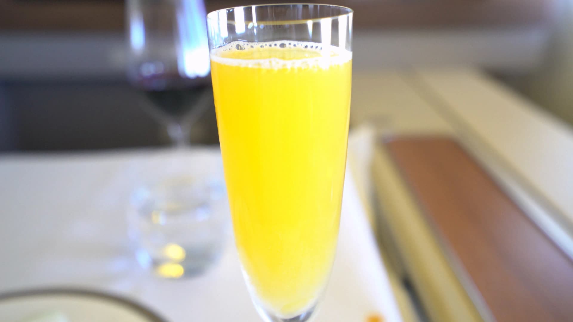 타이항공 퍼스트클래스 콘솔 위 플루트 잔과 IFE 화면, 창밖 햇빛이 들어오는 좌석 전경