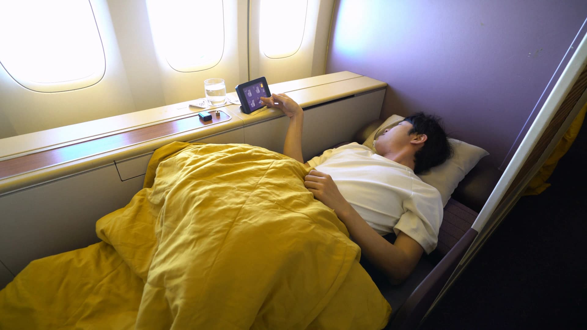 타이항공 퍼스트클래스 180도 풀플랫 시트에 금색 이불을 덮고 누운 모습, 승무원이 촬영