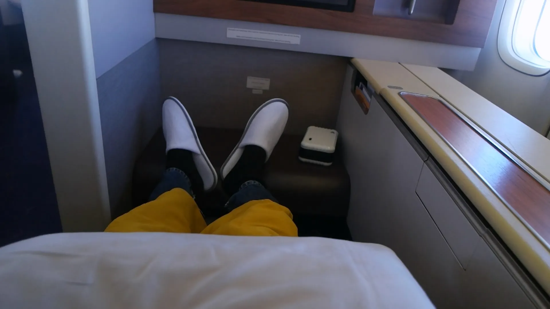 타이항공 퍼스트클래스 시트 피치 76인치 다리를 완전히 뻗은 모습, 슬리퍼 착용 금색 이불