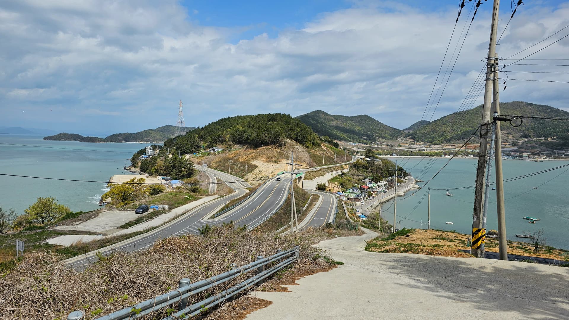 منظر علوي للطريق المتعرج الضيق المؤدي إلى نقطة المشاهدة مع البحر على الجانبين وقرية صغيرة