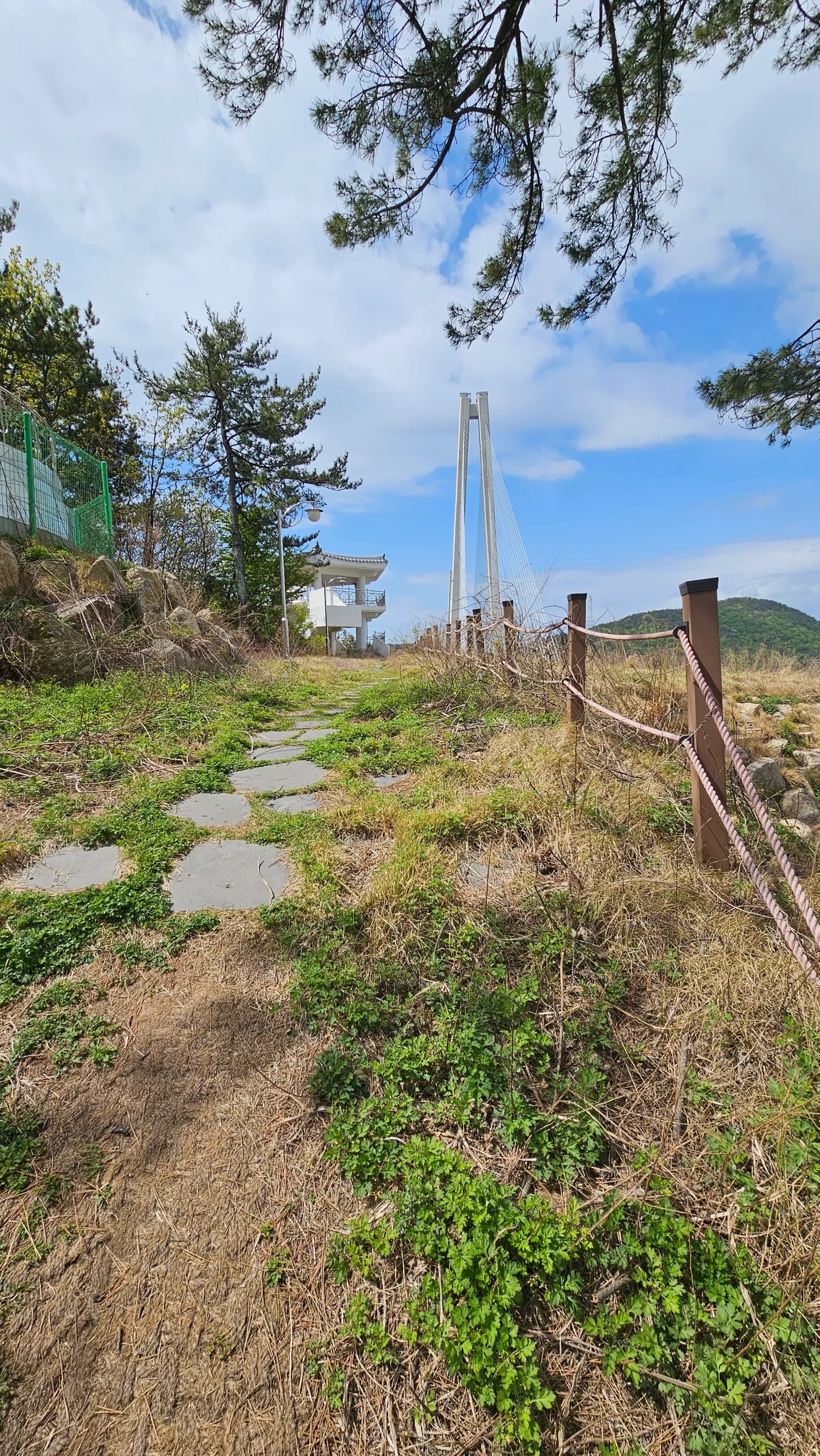 طريق حجري غير معبّد يصعد إلى مبنى نقطة المشاهدة الأبيض مع ظهور برج جسر جوبالدي في الخلفية