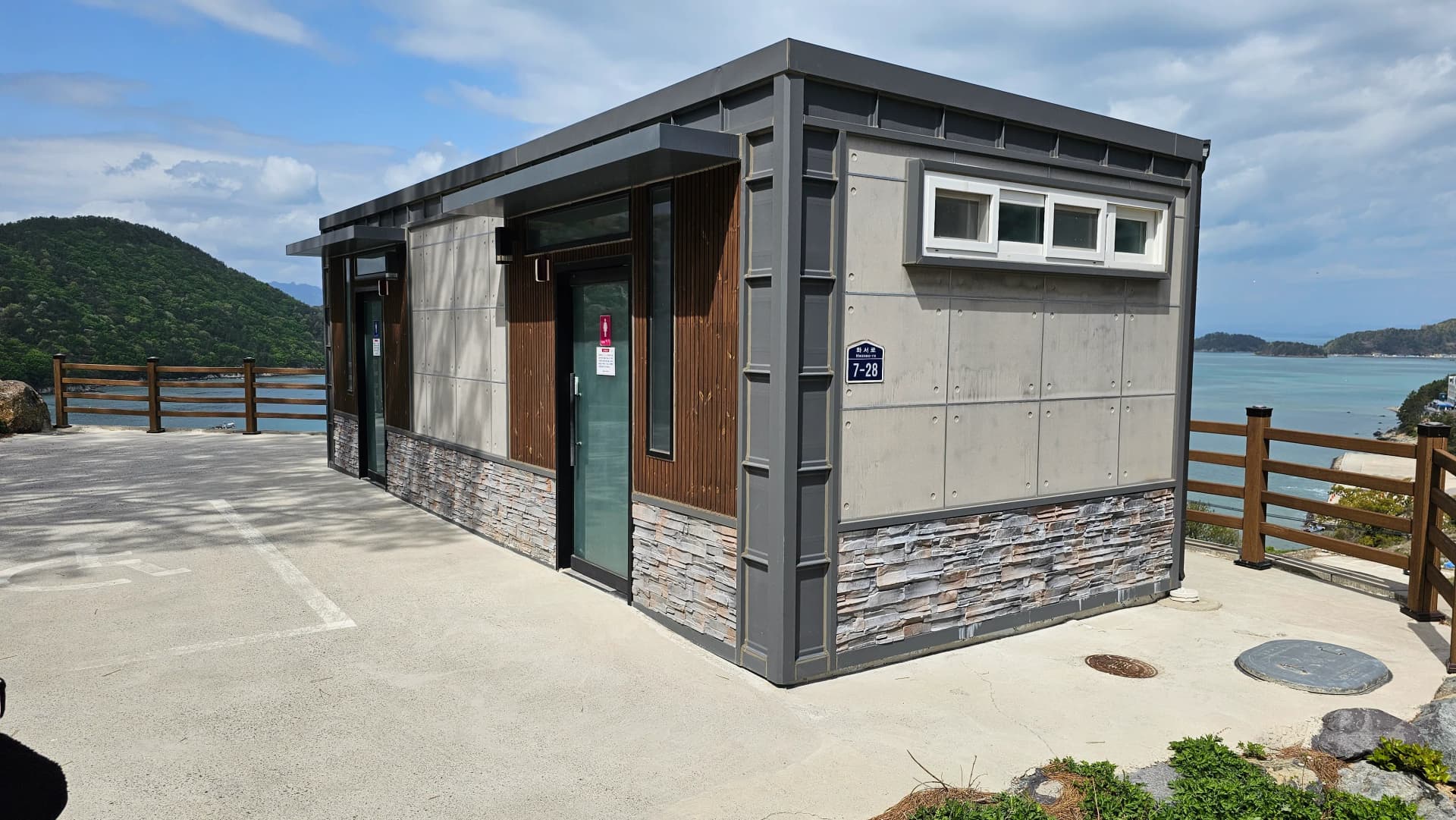 مبنى دورات مياه عامة نظيف بجانب موقف السيارات مع إطلالة على البحر في الخلفية