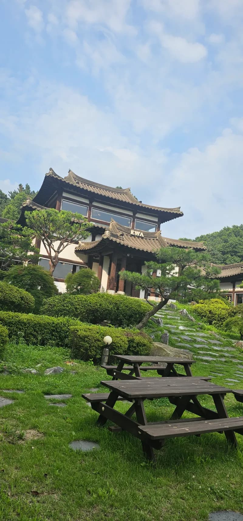 증평 카페 이와 전경 - 언덕 위에 위치한 웅장한 2층 한옥 건물과 푸른 잔디 마당 | 하이제이에스비