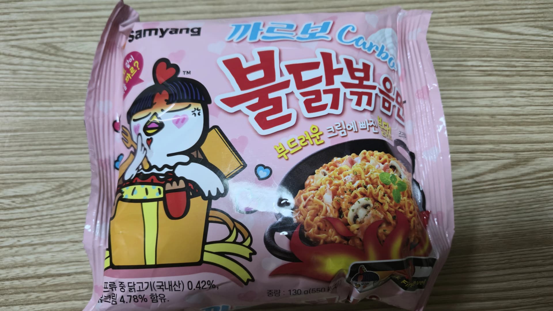 ಕಾರ್ಬೊ ಬುಲ್ಡಕ್ ಪ್ಯಾಕೇಜ್ ಮುಂಭಾಗ - ಗುಲಾಬಿ ಬಣ್ಣದ ಹಿನ್ನೆಲೆಯಲ್ಲಿ ಮುದ್ದಾದ ಬುಲ್ಡಕ್ ಕೋಳಿ ಚಿತ್ರವಿರುವ ಸಮ್ಯಾಂಗ್ ಫುಡ್ಸ್ ಪ್ಯಾಕೆಟ್ | 하이제이에스비