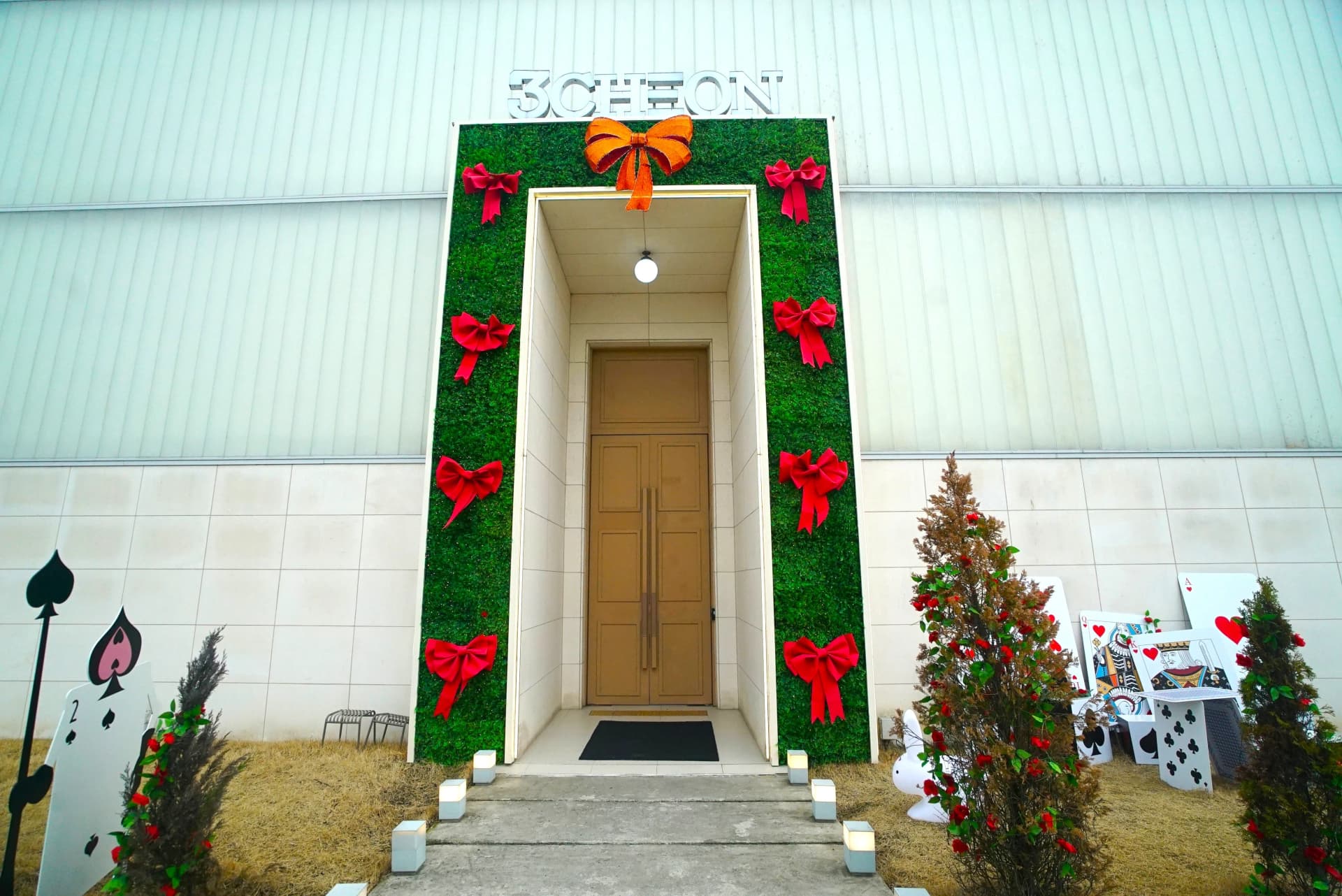Close-up of the grand entrance gate with tall doors flanked by lights and chess piece sculptures at this garden cafe