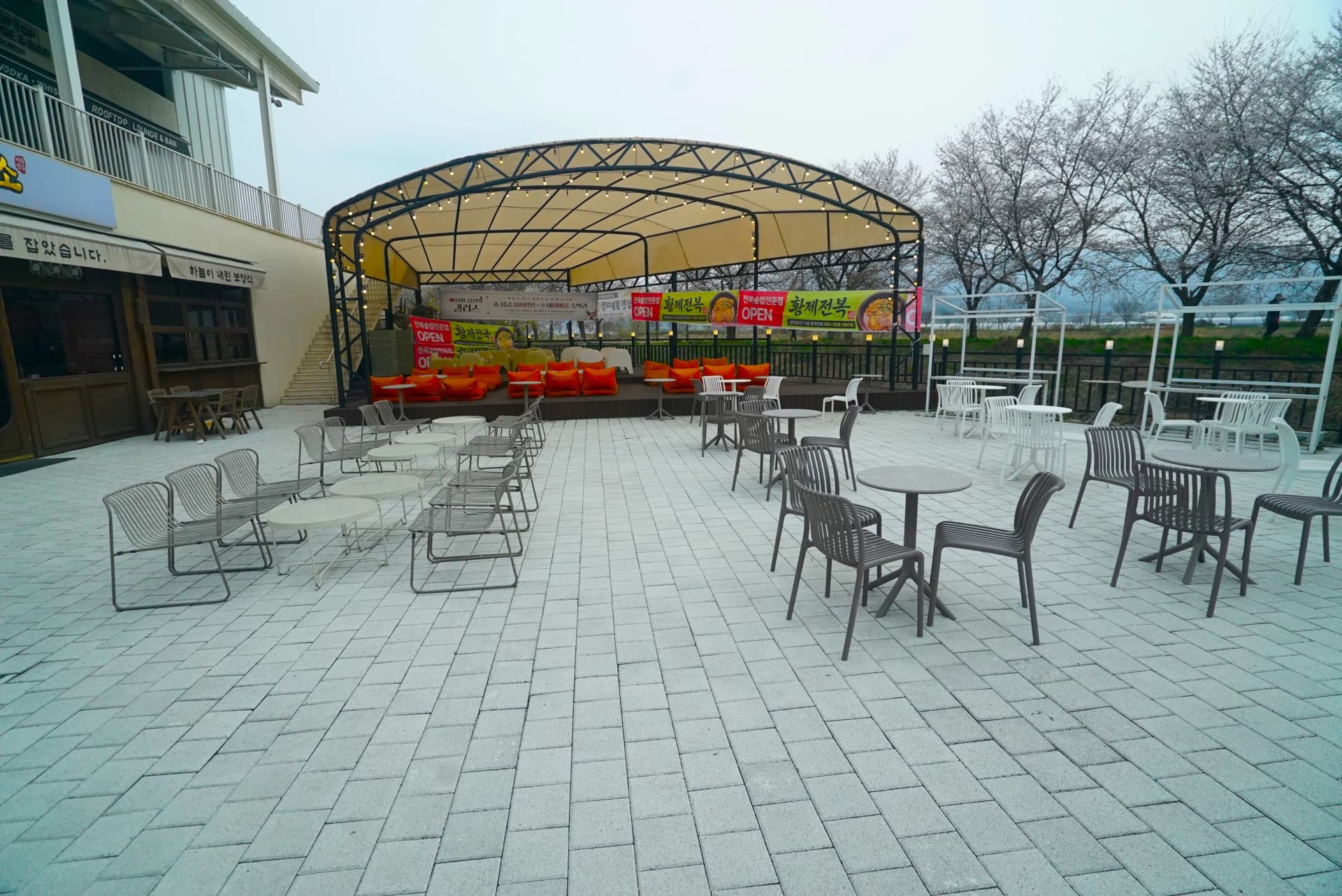 Outdoor terrace seating with arched canopy and orange cushion sofas at this garden cafe