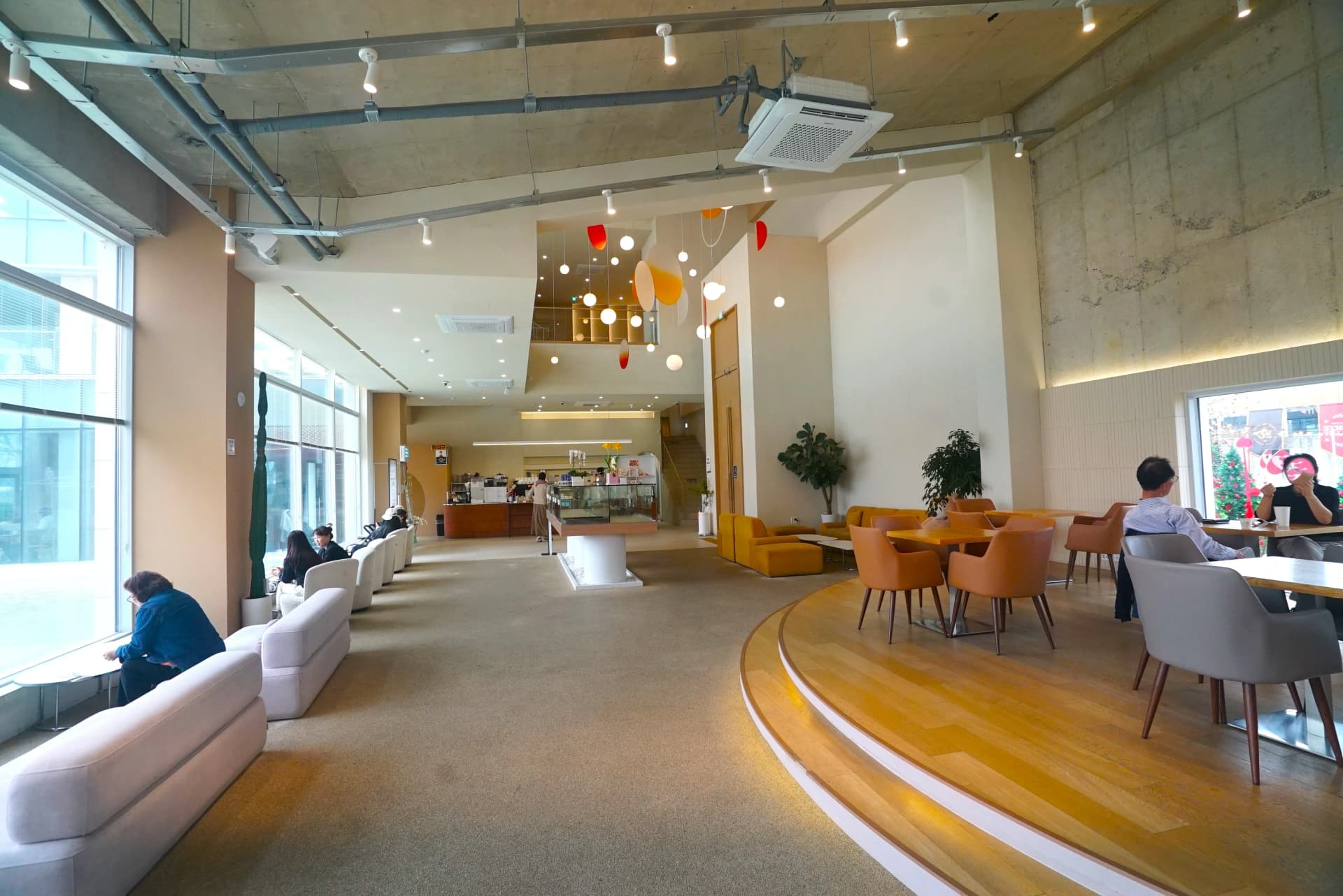 Ground floor interior of 3Cheon Village with double-height ceiling and orange circular pendant lights