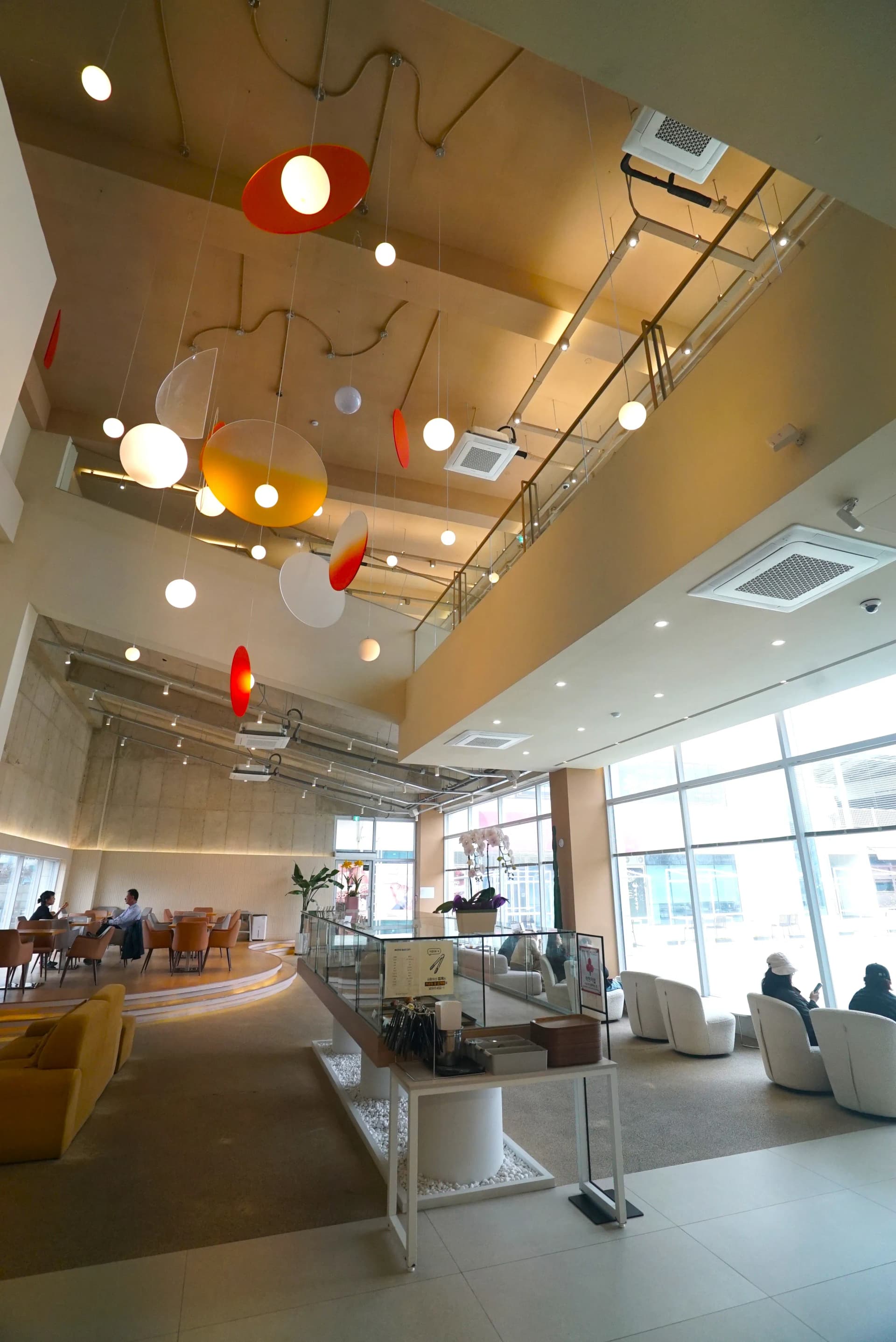 Window-side sofa seating and round platform tables inside the spacious modern cafe