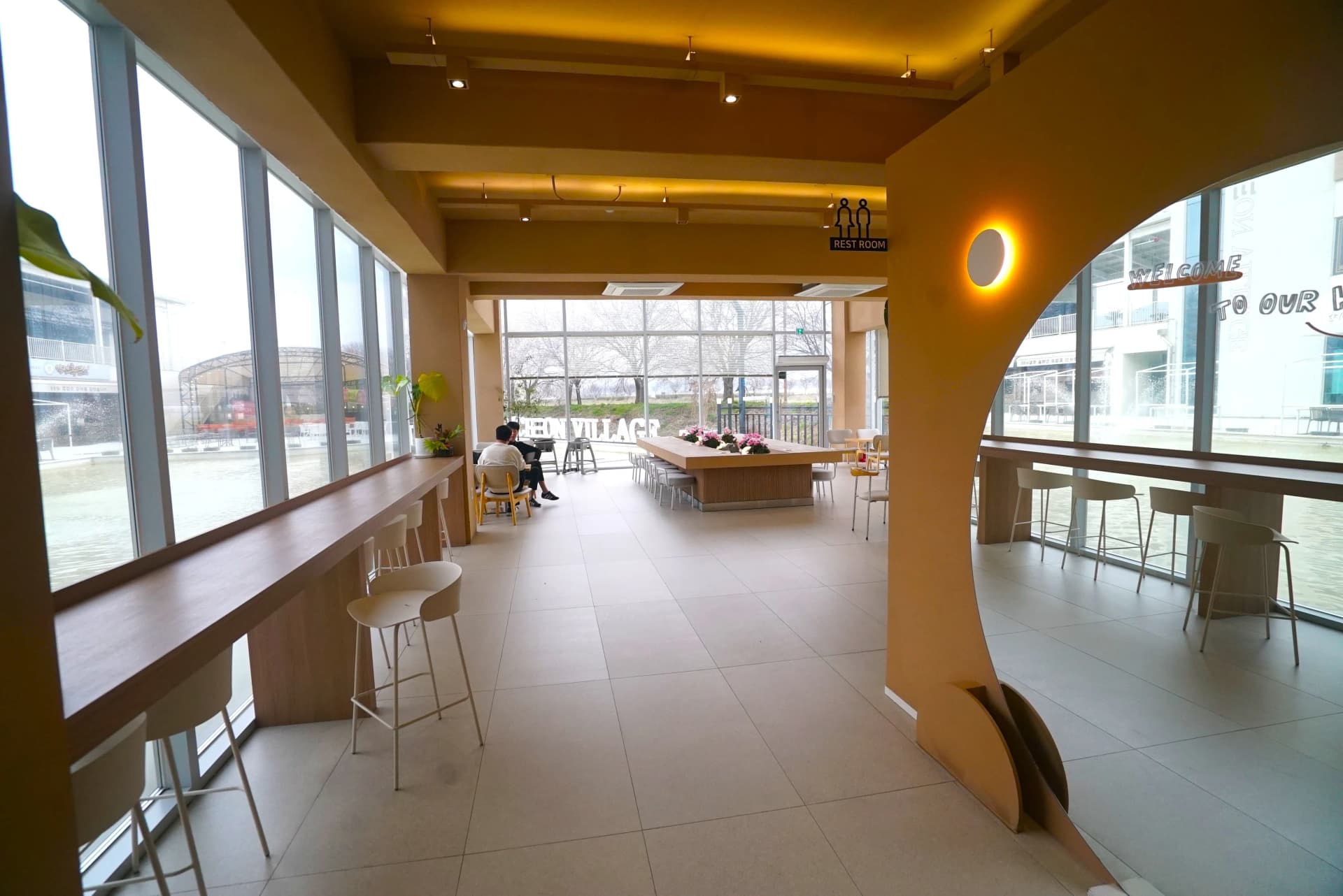 Three-sided glass-walled seating area with arched columns inside the spacious cafe
