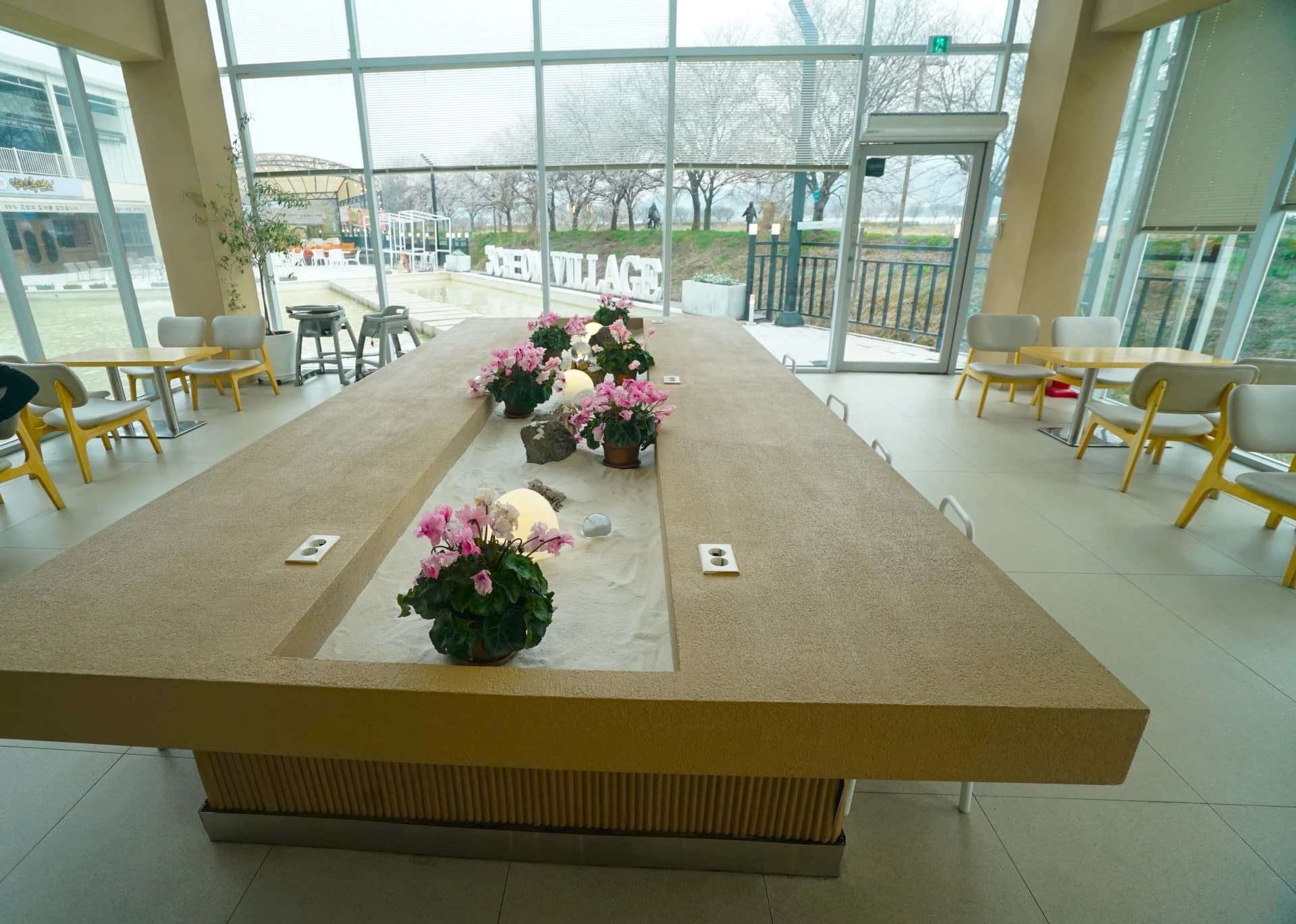 Round wall sconces and window-side bar seating with natural light at the modern cafe