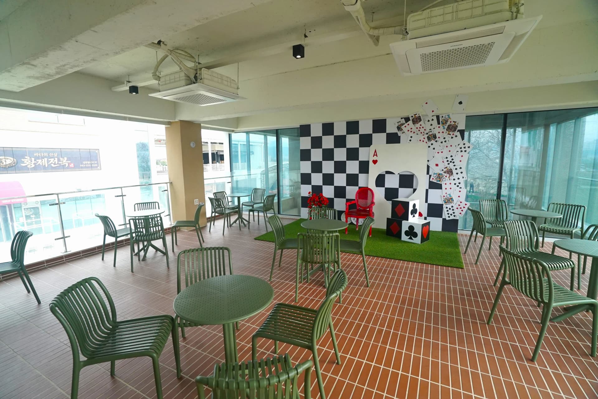 Semi-outdoor first floor terrace with khaki chairs and chequerboard photo zone at the themed cafe
