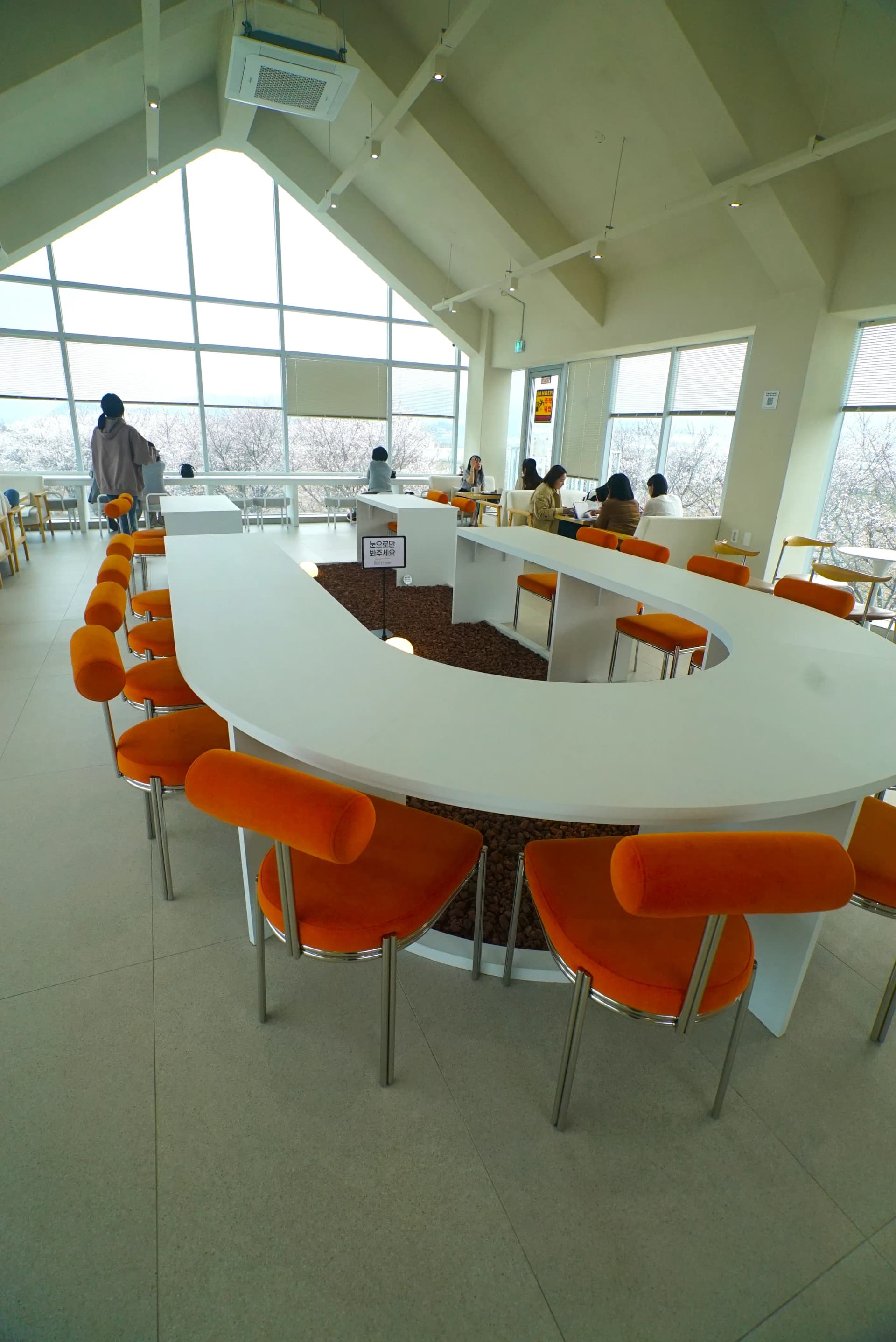First floor interior with A-frame ceiling and C-shaped counter table with orange chairs