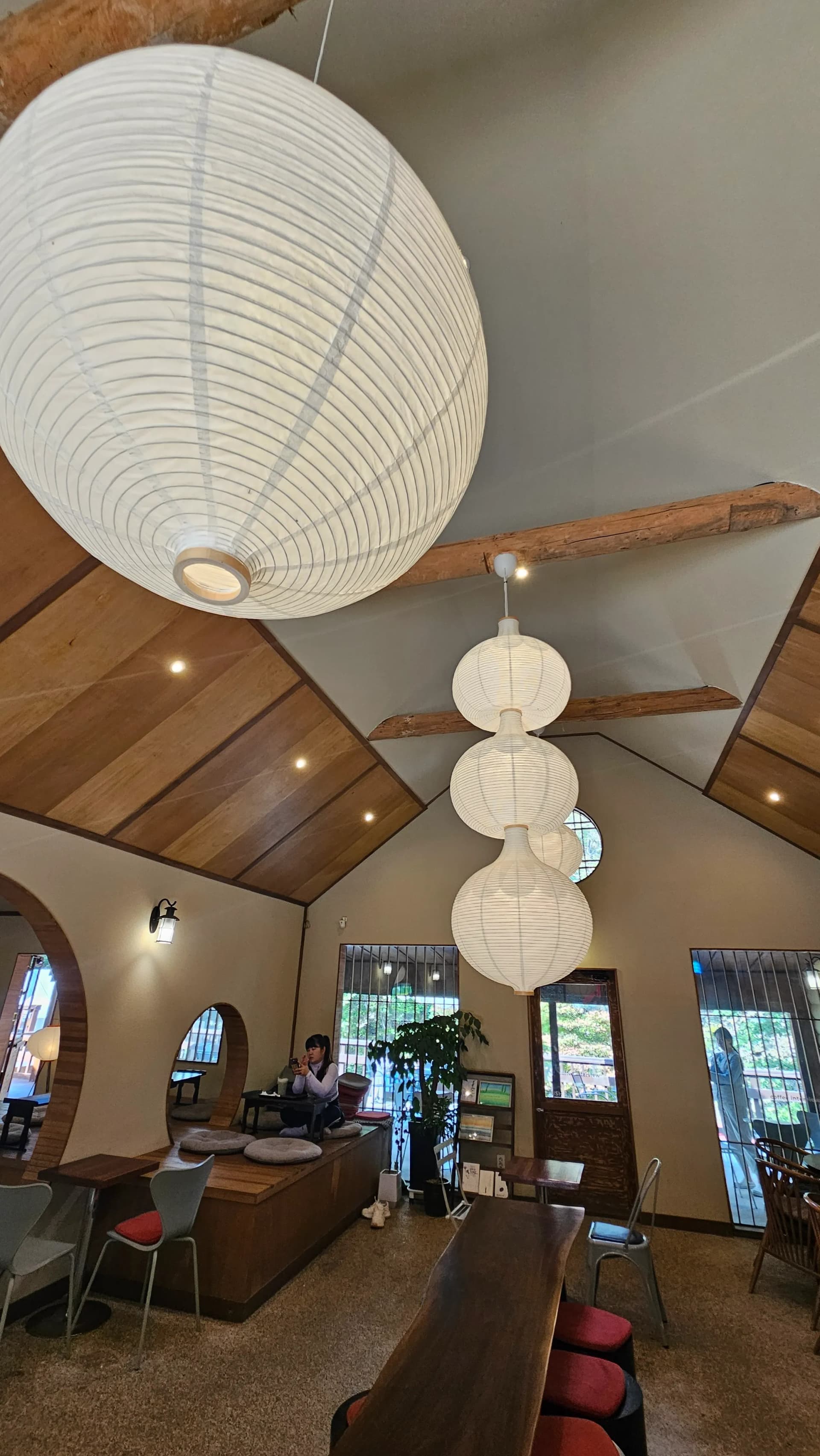 چھت پر لکڑی کے شہتیروں کے درمیان لٹکی ہوئی بڑی گول روشنیاں