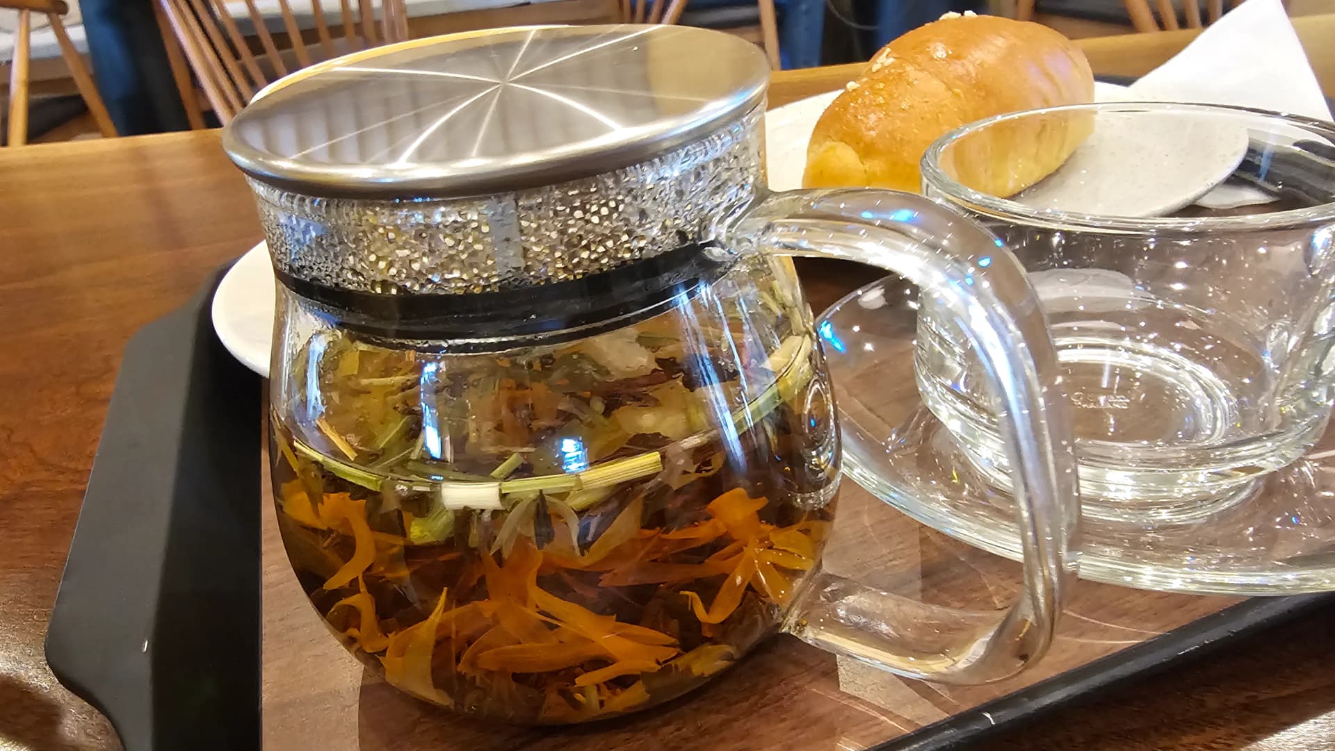 سٹرس لو کے شیشے کے برتن کا کلوز اپ، نارنجی پھولوں کی پتیاں اور سبز ہربز والی چائے