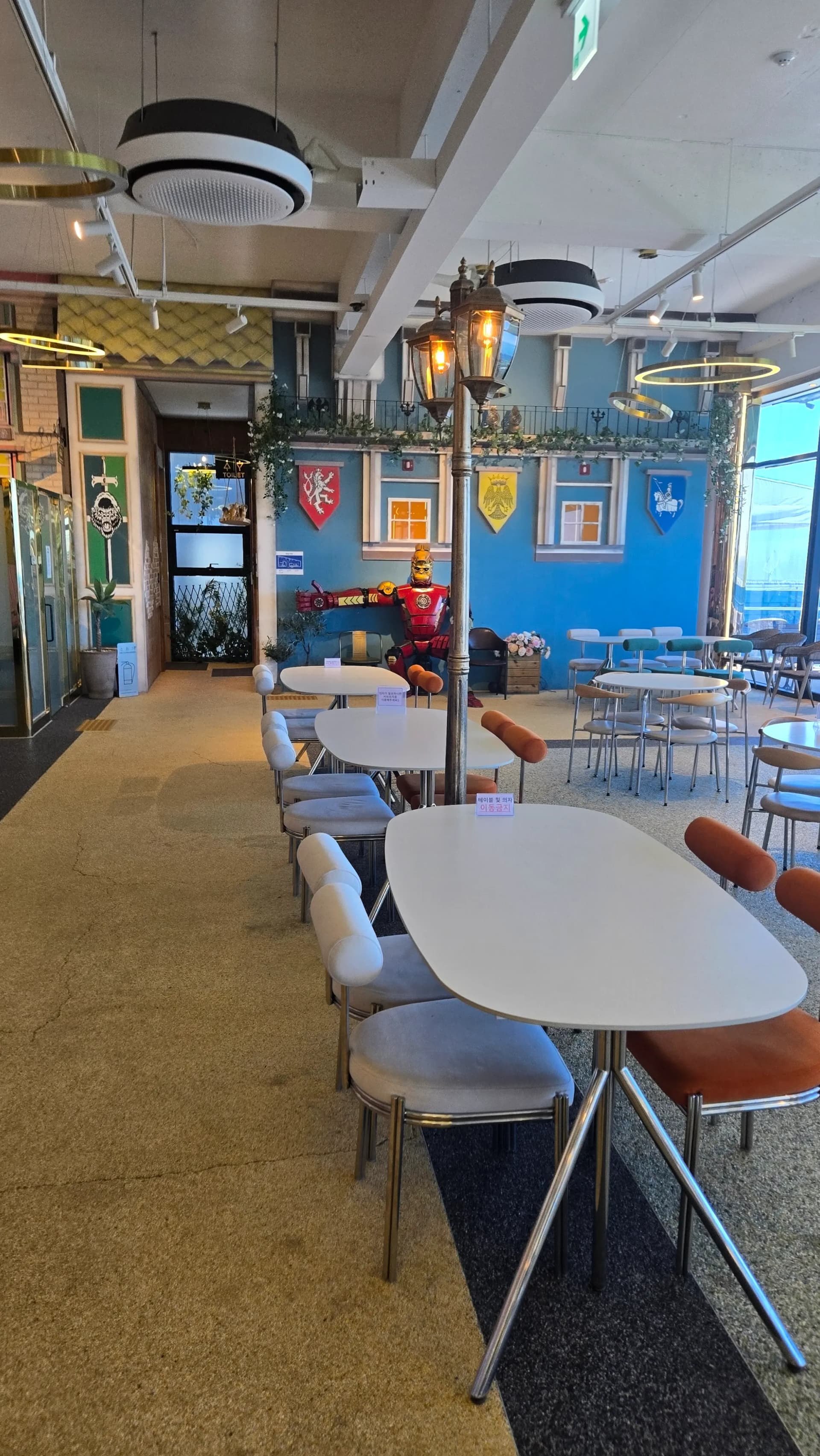 더킹 카페 1층 중세풍 테마 존 내부 - 파란 벽면 방패 장식 가로등 조명 아이언맨 피규어 - The King Cafe medieval themed interior zone with blue walls and shield decorations | 하이제이에스비