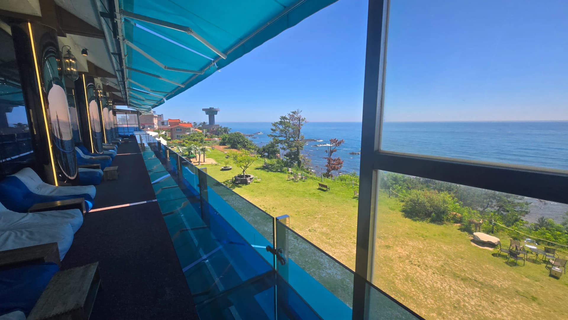 더킹 카페 2층 테라스 야외 좌석 - 유리 난간 너머 잔디 정원과 바다 전망 - The King Cafe 2nd floor terrace outdoor seating with ocean and garden view | 하이제이에스비