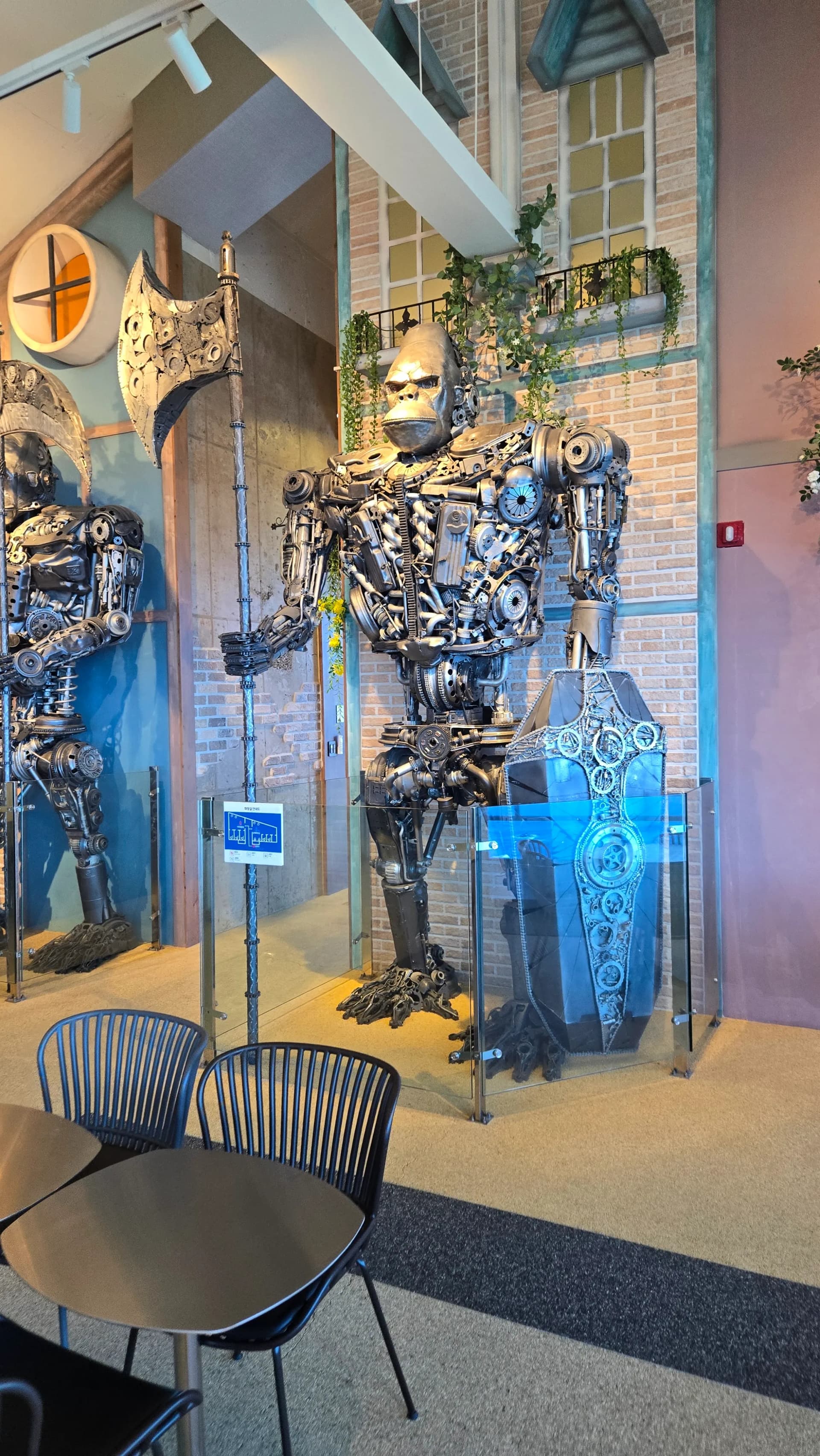 더킹 카페 금속 조형물 근접 촬영 - 도끼와 방패를 든 거대한 피규어 유리 케이스 - The King Cafe close-up of giant metal figure holding axe and shield in glass case | 하이제이에스비