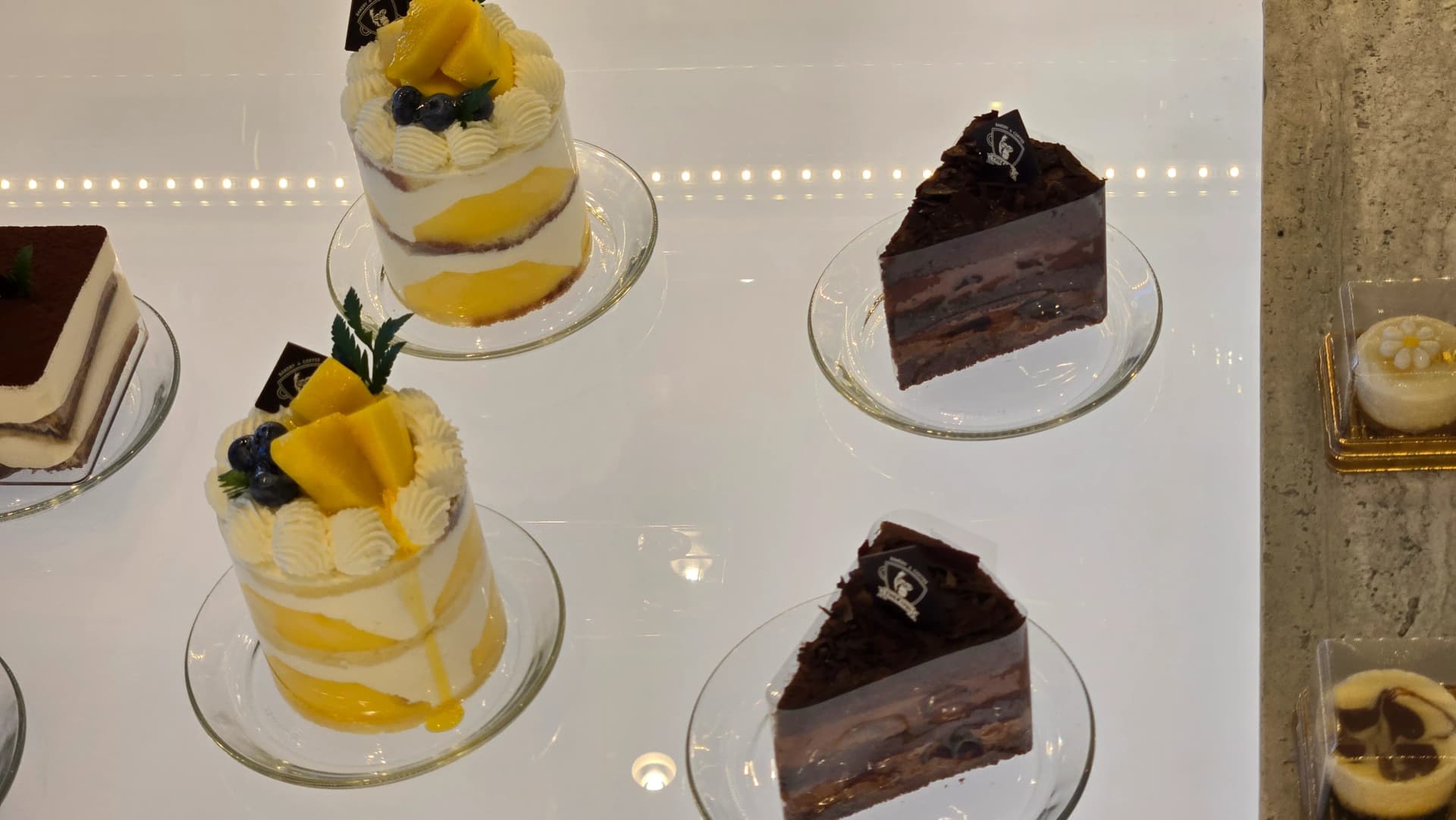 더킹 카페 베이커리 진열대 - 망고 케이크 초콜릿 케이크 티라미수 조각 케이크 - The King Cafe bakery display with mango cake chocolate cake and tiramisu slices | 하이제이에스비