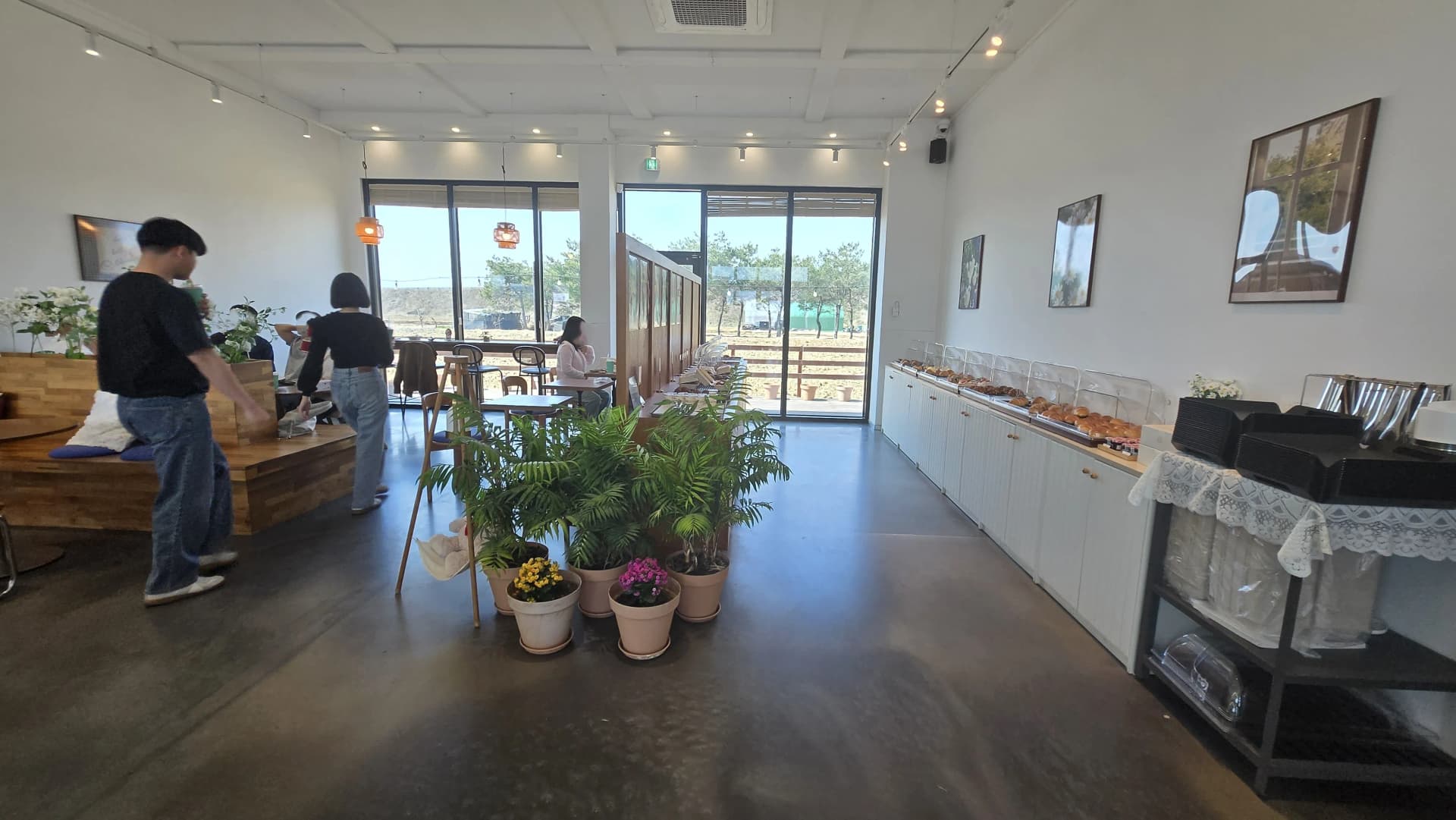 Inside Toseong Village cafe with white walls and grey floor, bakery display on the right and counter on the left