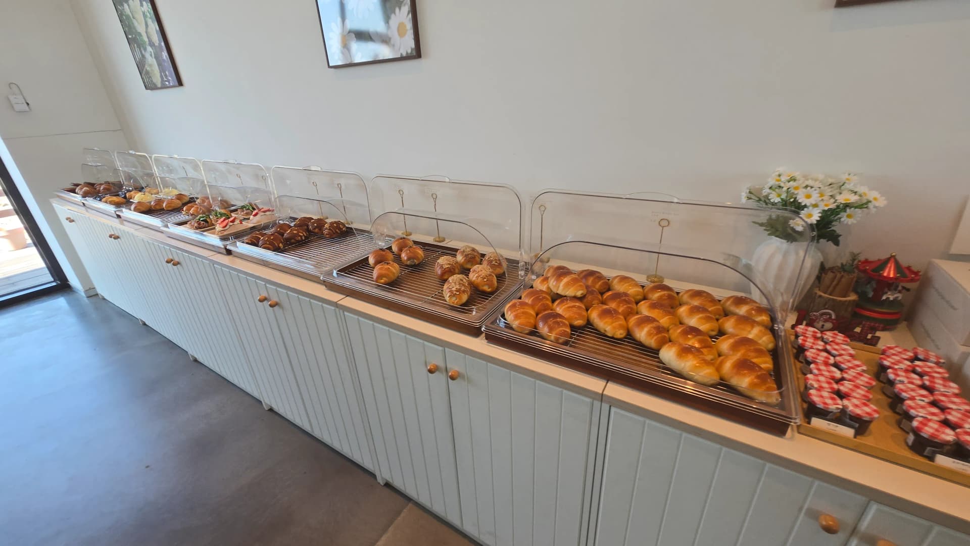 Full artisan bakery display at Toseong Village with trays of salt bread, financiers and croissants sorted by variety