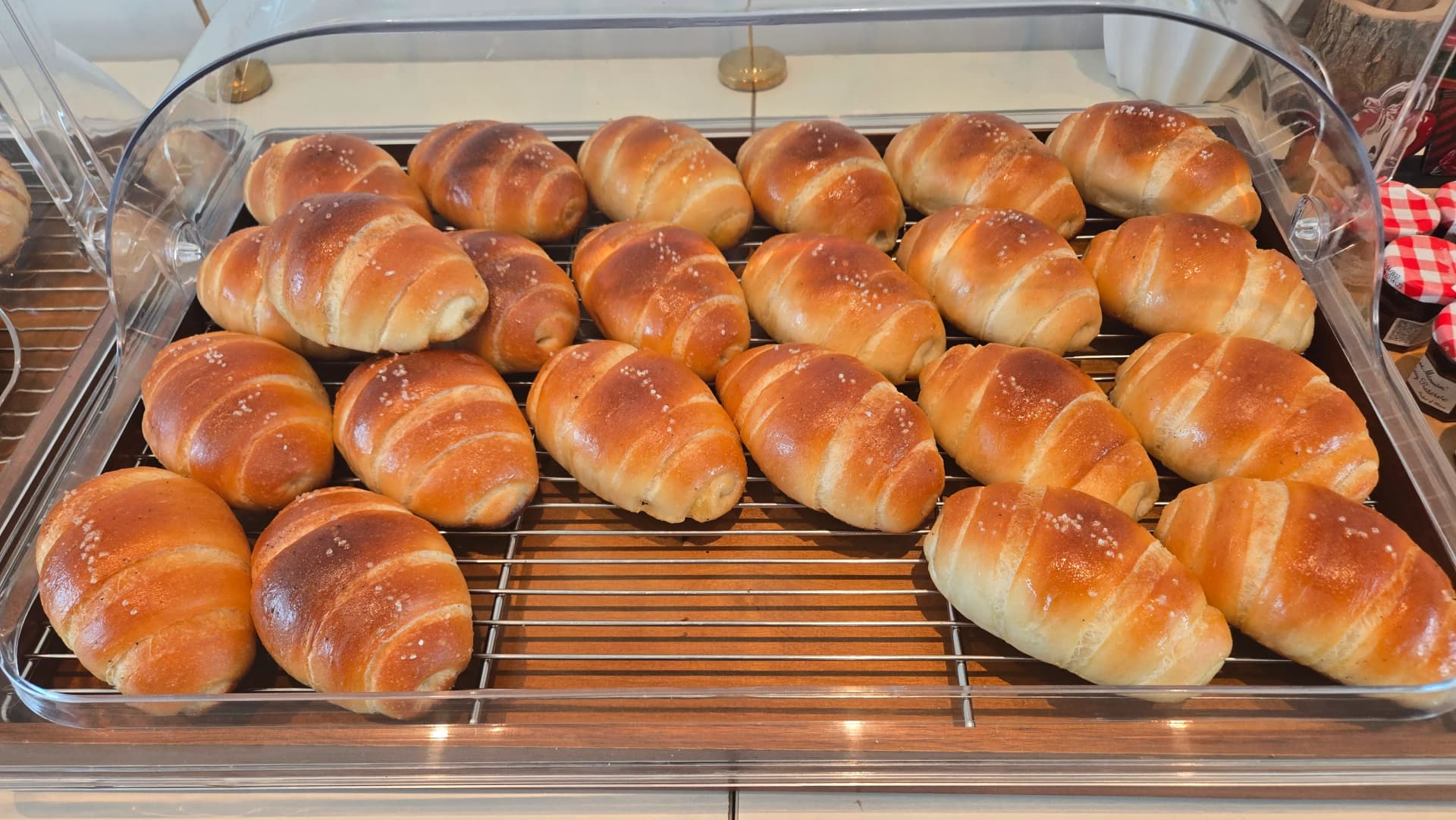 Plain salt bread rolls packed tightly on a tray with coarse salt crystals glistening on golden-brown tops