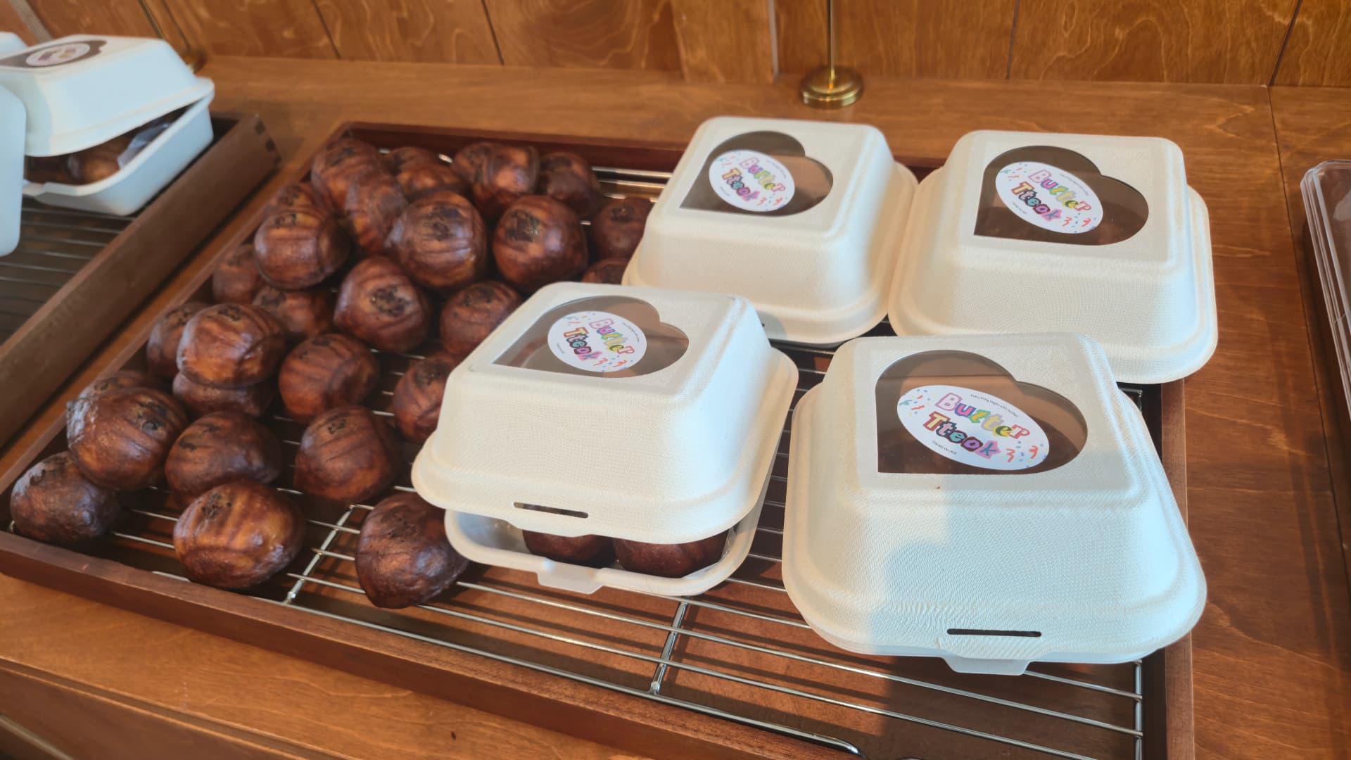 Butter mochi rounds priced at about two dollars each, next to a gift box with a heart-shaped window