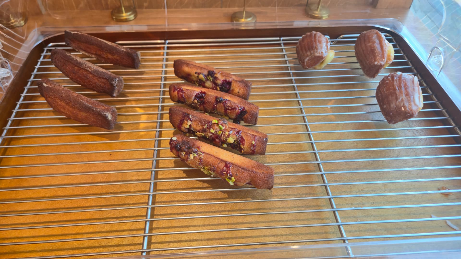 Raspberry financier in the centre flanked by remaining plain financiers and madeleines on the tray