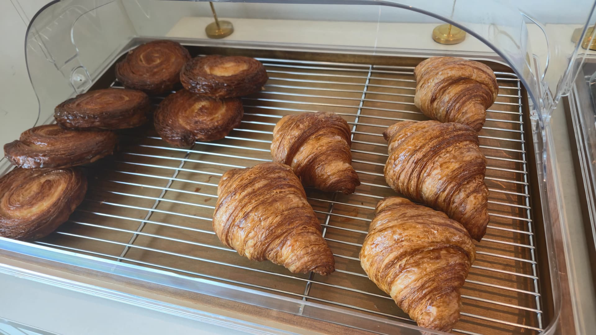 Flaky croissant with defined layers next to a crookie showing chocolate layer through the cross-section