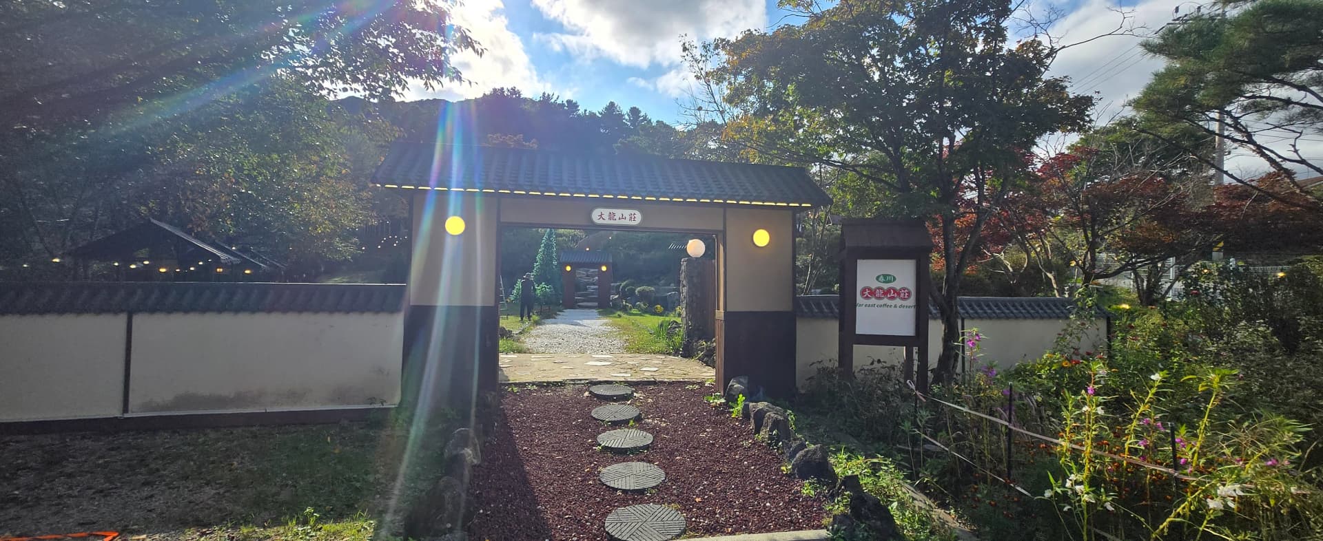 Pemandangan pintu masuk Daeryong Sanjang di Chuncheon, gerbang gaya Timur dan kafe ala rumah persinggahan dikelilingi pokok rimbun | 하이제이에스비