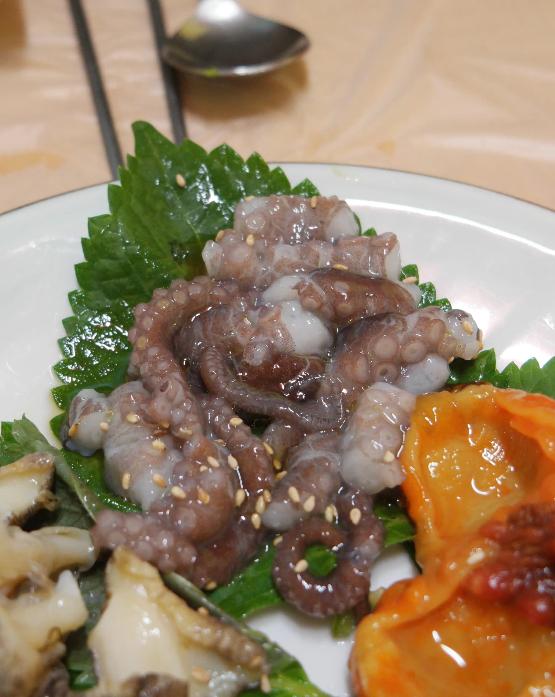 깻잎 위에 올려진 산낙지 - 참깨가 뿌려져 있고 빨판이 꿈틀거리는 날것 상태의 낙지 | 하이제이에스비