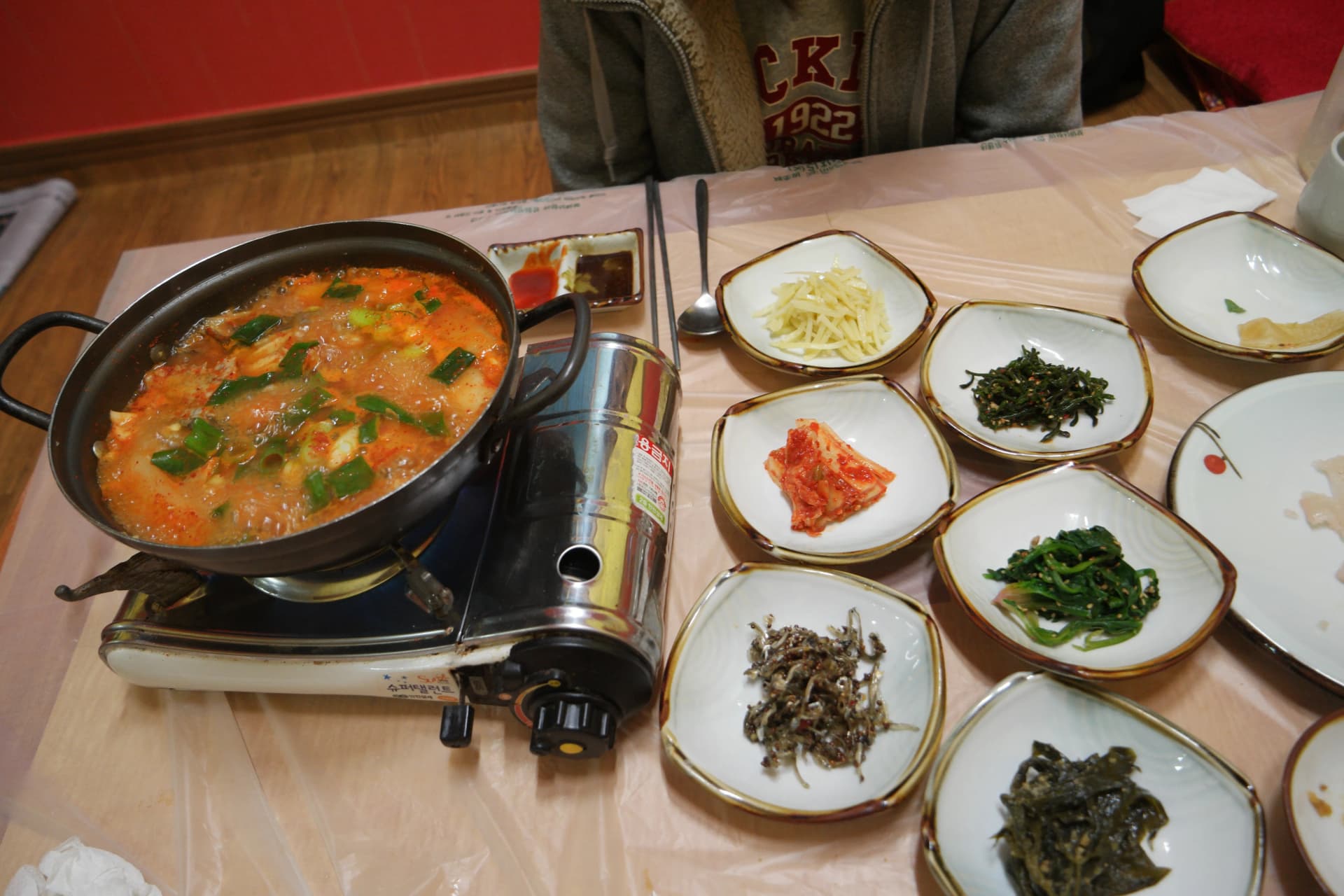 회 뜨고 남은 생선뼈로 끓인 생선찌개와 콩나물무침, 김치, 시금치나물, 멸치볶음 등 한국식 반찬이 차려진 밥상 | 하이제이에스비