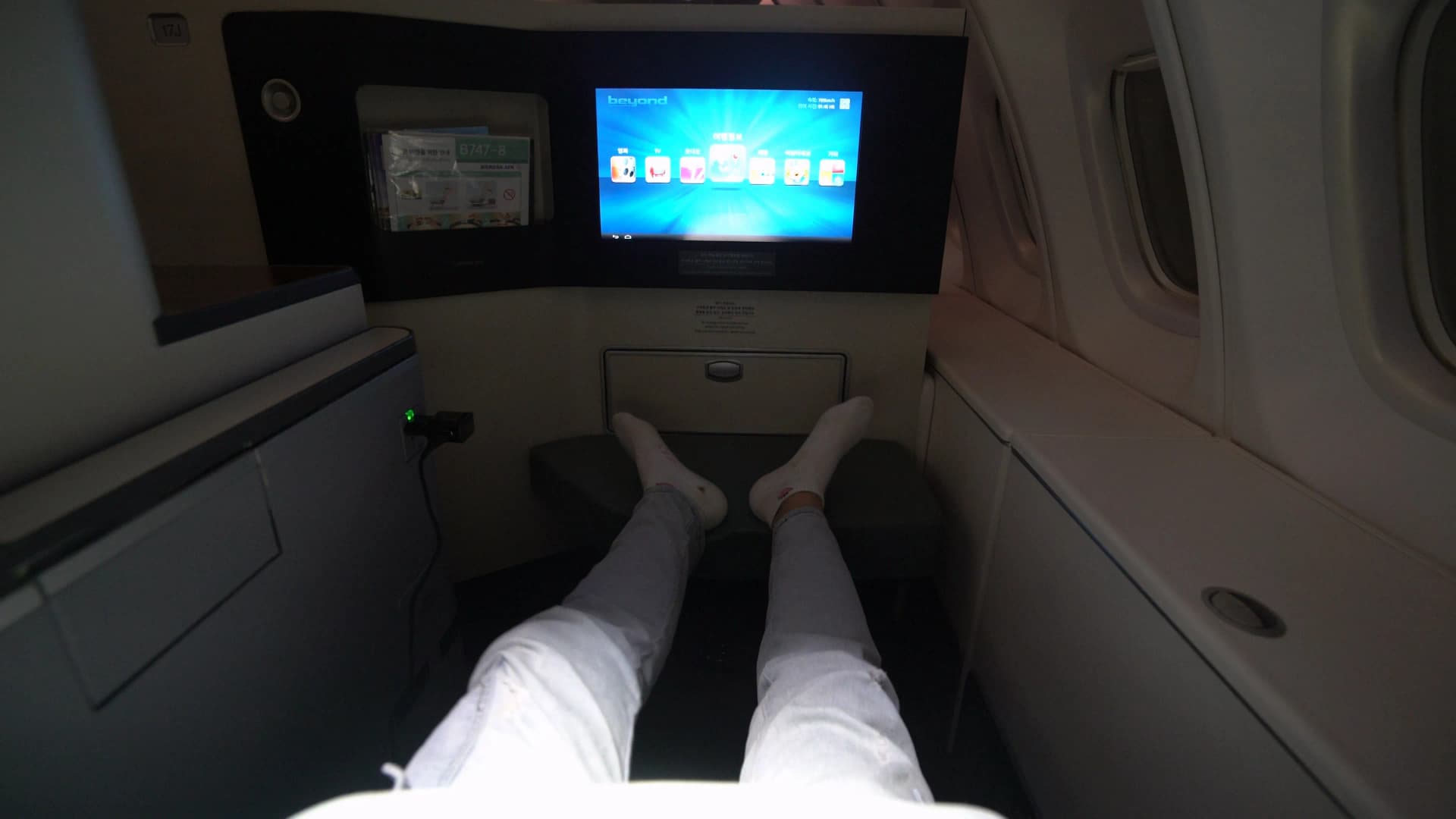 Legs stretched out in Korean Air 747-8i Prestige Class lie-flat seat showing generous legroom to footrest
