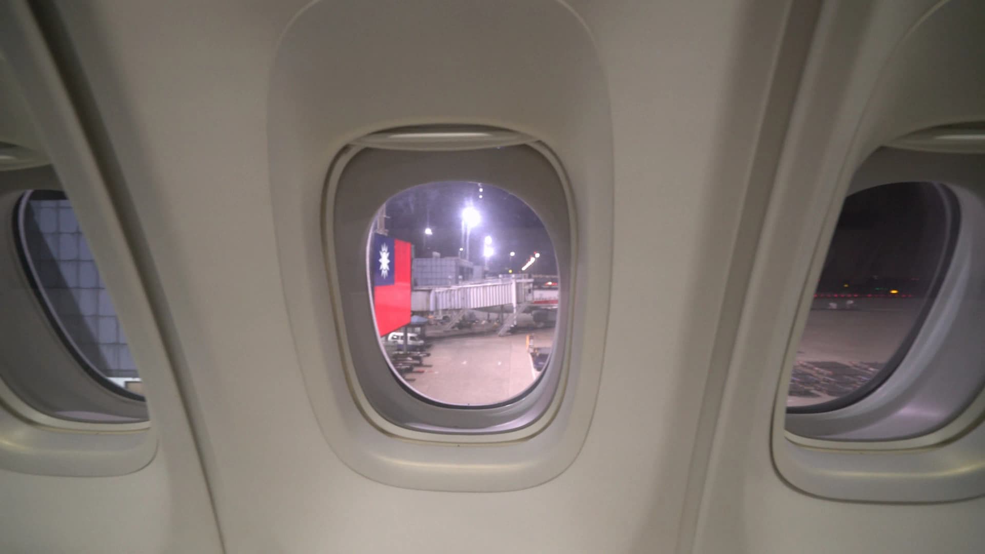 Four cabin windows at Korean Air 747-8i upper deck Prestige Class window seat showing Taoyuan Airport runway lights at night