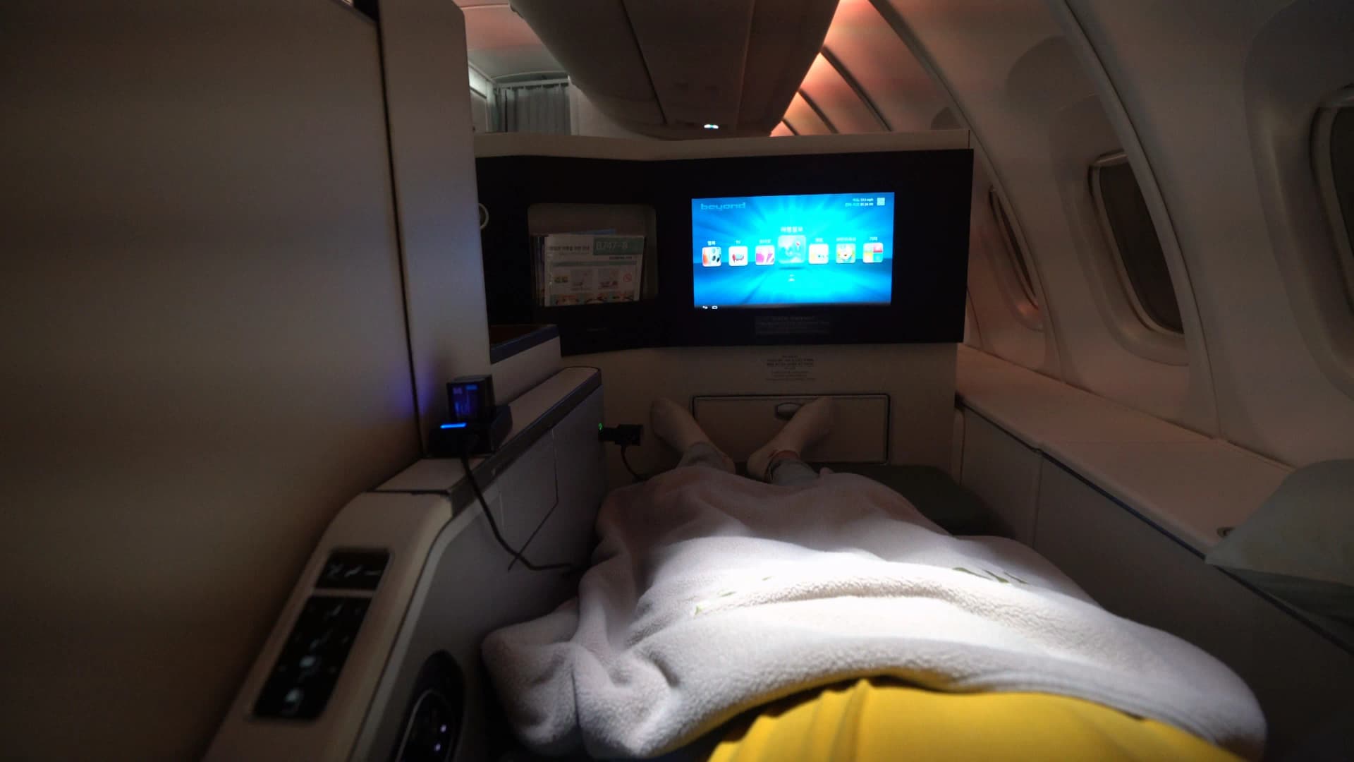 Korean Air 747-8i Prestige Class lie-flat seat fully reclined to 180 degrees with blanket draped and monitor on